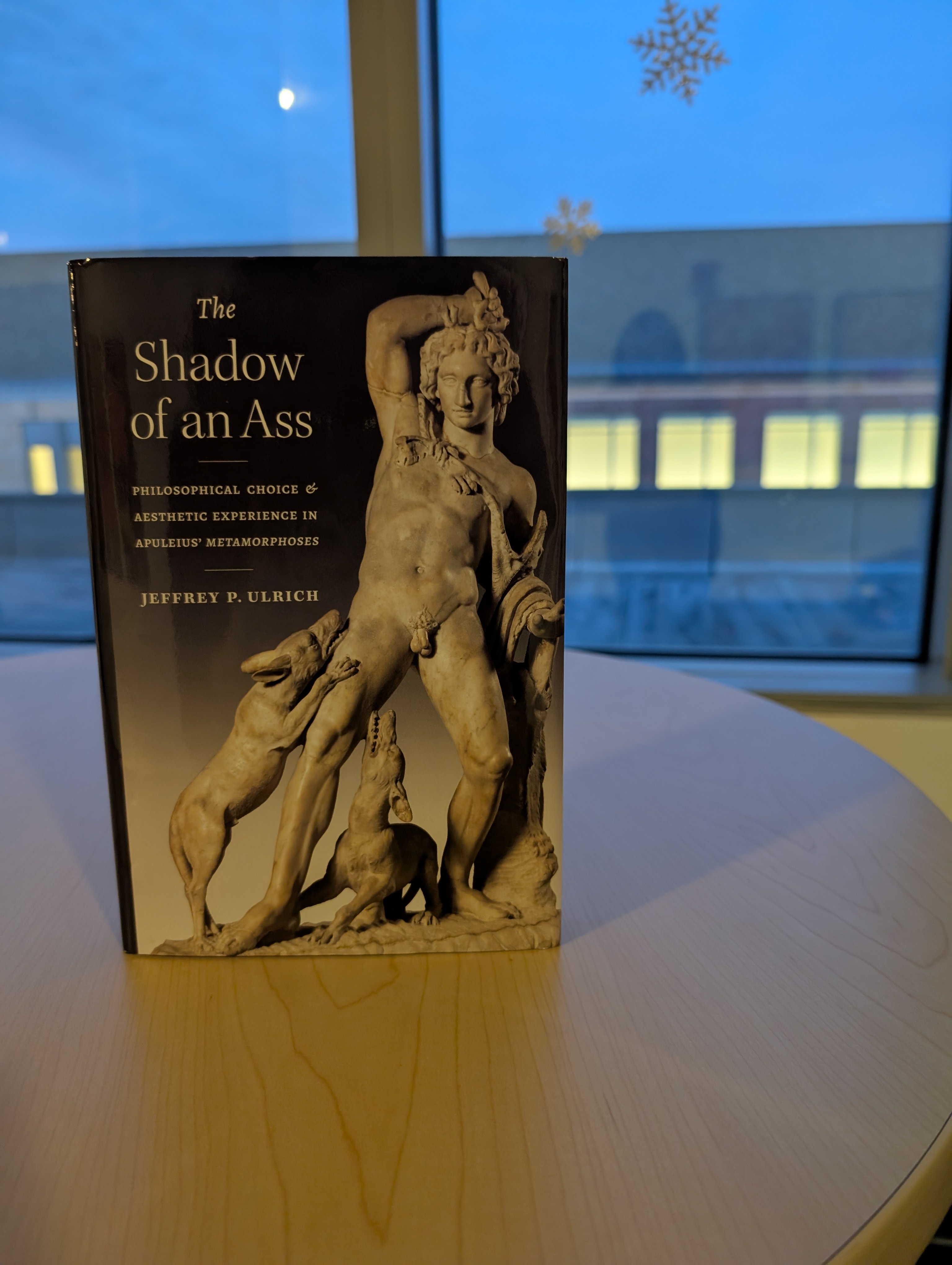 The image shows the book "The Shadow of an Ass (Philosophical Choice and Aesthetic Experience in Apuleius' Metamorphoses)" sitting on a table